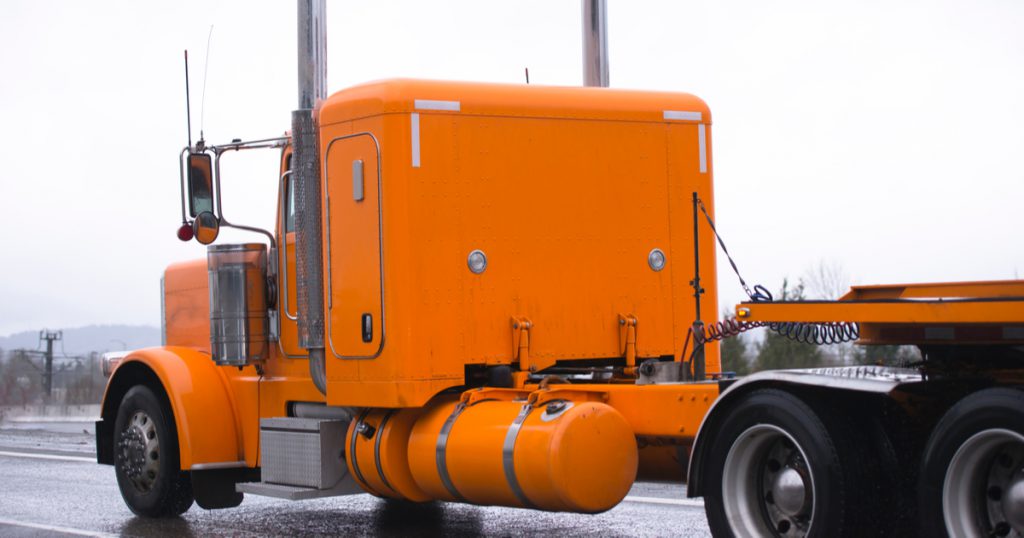 Orange truck in rain making money as an owner operator with trucking management software