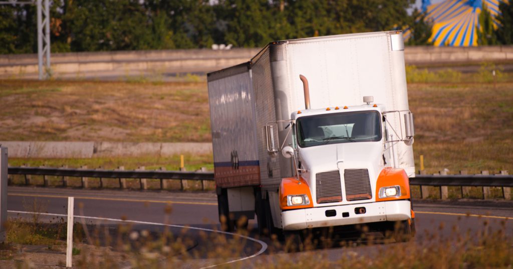 orange and white truck on interstate saving on owner operator expenses